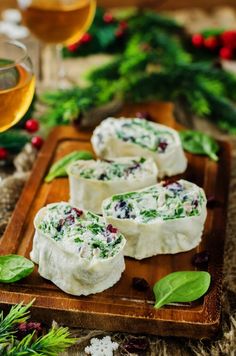 three pieces of appetizers on a wooden tray with holly wreaths in the background