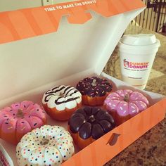 there are many donuts in the box with frosting and sprinkles