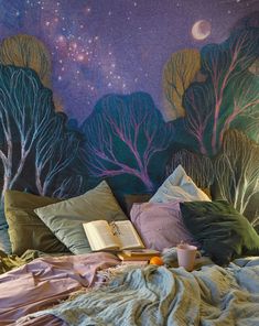 a bed with pillows and blankets on it in front of a wall painted with trees