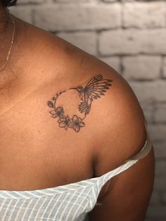 a woman with a tattoo on her shoulder has a bird and flowers in the shape of a circle