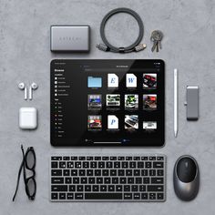 a tablet, keyboard, mouse and other items are arranged on a concrete table top