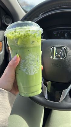 a person holding a starbucks cup in their hand while sitting in the driver's seat of a car