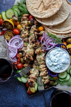 a platter with grilled chicken, vegetables and pita bread