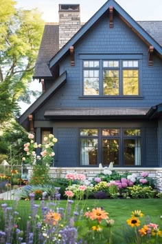 a blue house with lots of flowers in the front yard