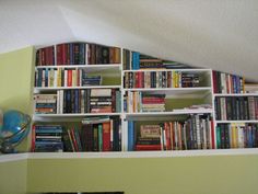 a bookshelf filled with lots of books in a room next to a wall