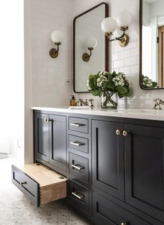 a bathroom with black cabinets and white tiles on the walls, two mirrors above the sink