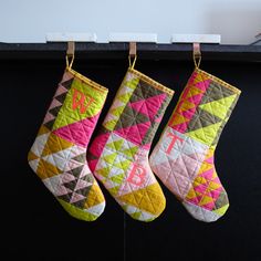 three colorful christmas stockings hanging from hooks