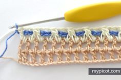 the crochet stitch is being worked on by a yellow handled knitting needle with blue and white yarn