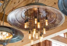 a chandelier hanging from the ceiling with light bulbs on it in a barn