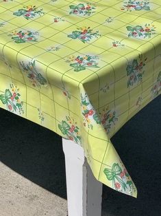 a yellow table cloth with flowers and leaves on it sitting on a white wooden bench