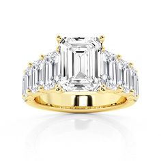 an emerald cut diamond ring with baguetts on the shoulders and side stones in yellow gold