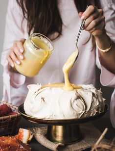 a woman is spreading icing on a cake