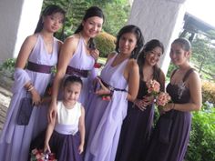 a group of women standing next to each other wearing purple dresses and holding bouquets