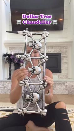 a woman sitting on the floor holding up a model of a structure in front of her face