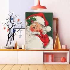 there is a christmas painting on the wall next to a shelf with candles and decorations