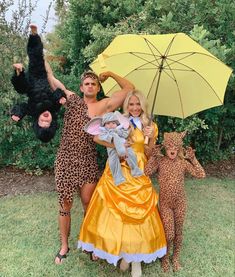 three people dressed in costumes posing with an umbrella