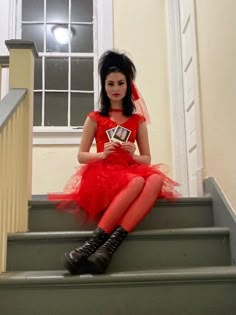 a woman in a red dress sitting on some stairs