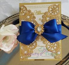 there is a card with a blue bow on it next to a flower and a silver tray