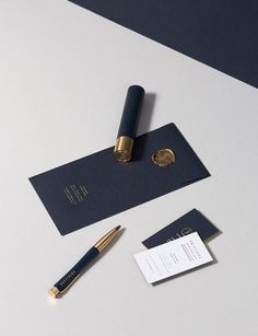 a fountain pen and some business cards on a white table with a blue envelope next to it