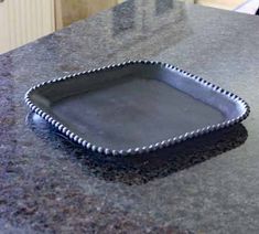 a square metal tray sitting on top of a granite countertop next to an oven