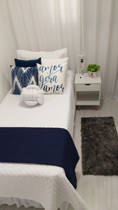 a white bed sitting next to a night stand with pillows and blankets on top of it