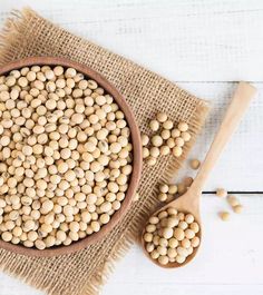 a bowl filled with chickpeas next to two wooden spoons