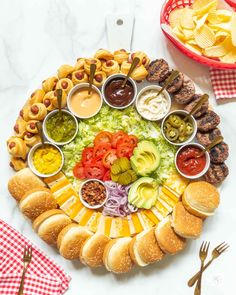 a platter filled with sandwiches, dips and condiments on top of a table