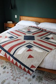 a bed with a quilt on top of it in a room that has green walls