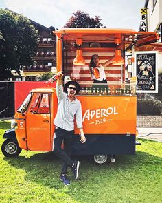 a man standing in front of an orange food truck