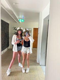 two young women dressed in sailor hats are taking a selfie