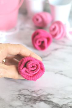 a hand holding a pink flower on top of a marble counter