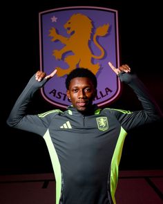 a soccer player poses for a photo in front of the as roma crest with his hands on his head