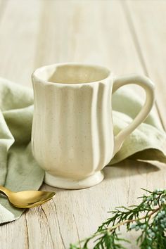 a white coffee cup sitting on top of a wooden table next to a green napkin