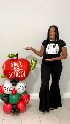 a woman standing next to a balloon shaped like an apple with the words back to school written on it