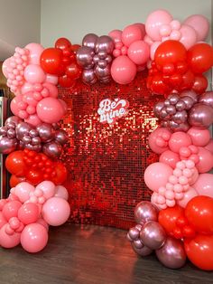 the balloon arch is decorated with red, silver and pink balloons