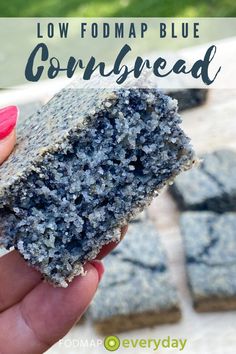 a hand holding up a piece of blue cornbread with the words low fodmap