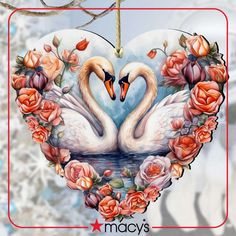 two swans in a heart shaped frame with roses on the bottom and an ornament hanging from a tree