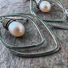 A pair of genuine freshwater pearls are carefully wrapped in sterling silver wire. The luminous pearls are very pale peach in color. The pair is framed by sterling silver petal shapes which I have formed, soldered, and textured by hand. The earrings hang from handformed Sterling Silver earwires. The silver has been oxidized and polished to create the patina finish. Be sure to see all photos and video for size and color reference. Total Earring Length: About 1 and 3/4" Handmade Pear-shaped Silver Jewelry, Handmade Silver Pearl Earrings In Pear Shape, Handmade Silver Pear-shaped Pearl Earrings, Silver Teardrop Wire Wrapped Pearl Earrings, Color Reference, Pale Peach, Patina Finish, Handmade Sterling Silver, Silver Wire