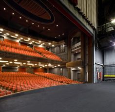 an empty auditorium with orange seats and lights