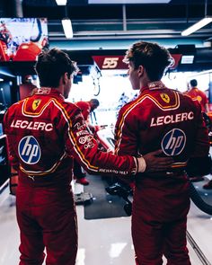 two men in red racing suits standing next to each other