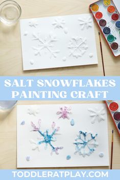 two snowflakes painted on paper with watercolors and paintbrushes next to them