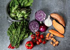 various vegetables are laid out on the counter top, including lettuce, carrots, and red onions