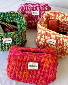 four woven baskets with labels on them sitting on a white tablecloth covered table top