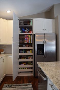 an open pantry in the corner of a kitchen with white cabinets and stainless steel appliances