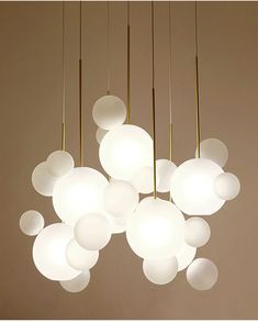 a chandelier with white balls hanging from it's sides and lights on the ceiling