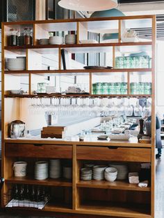 an open kitchen with lots of dishes on the counter and hanging lights above it in a restaurant