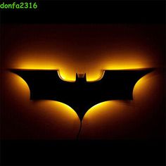 the dark knight batman logo is lit up with yellow light from below it, and on top of a black background