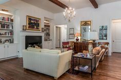 a living room filled with furniture and a fire place under a chandelier in front of a fireplace