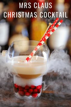 a glass filled with liquid sitting on top of a table next to some red and white striped straws