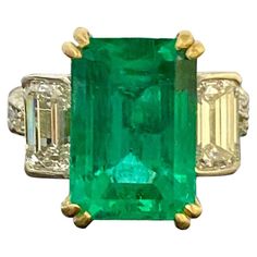 No description prDekara Designs Collection Metal- 90% Platinum, 10% Iridium. 18K Yellow Gold, .750. Stones- GIA Certified Colombian Emerald 6.78 Carats, 2 GIA Certified Emerald Cut Diamonds, D Color VS2 Clarity 1.03 Carats, D Color SI1 Clarity E Color SI1 Clarity 1.01, Carats, 14 Round Diamonds F-G Color VS1-VS2 Clarity, 1.14 Carats. 9.96 Total Carats. Colombian Emerald Report Number 6207969167 D VS2 1.03 Carat Diamond Report Number 6415999914 D SI1 1.01 Carat Diamond Report Number 6415203938 Ri White Gold Emerald Ring, Colombian Emerald Ring, Emerald Set, Emerald Ring Gold, Vintage Cocktail Ring, Handmade Engagement Rings, Platinum Diamond Rings, Emerald Diamond Ring, Colombian Emeralds